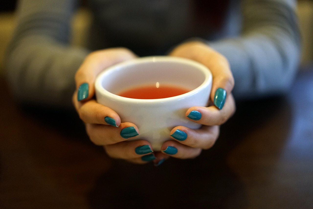 hands holding warm herbal tea to ease nighttime anxiety